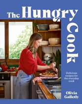 Een vrouw in een rode trui en spijkerbroek bereidt eten in een keuken. Titel: The Hungry Cook.