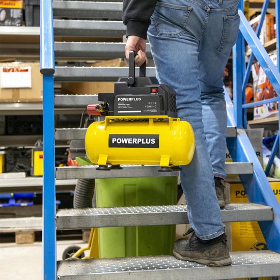 Persoon in spijkerbroek draagt een gele Powerplus compressor met zwarte handgreep.
