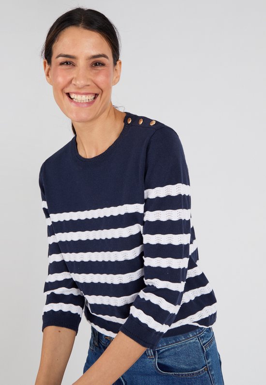 Femme portant un pull rayé bleu marine et blanc avec des boutons dorés sur l'épaule gauche, souriante.