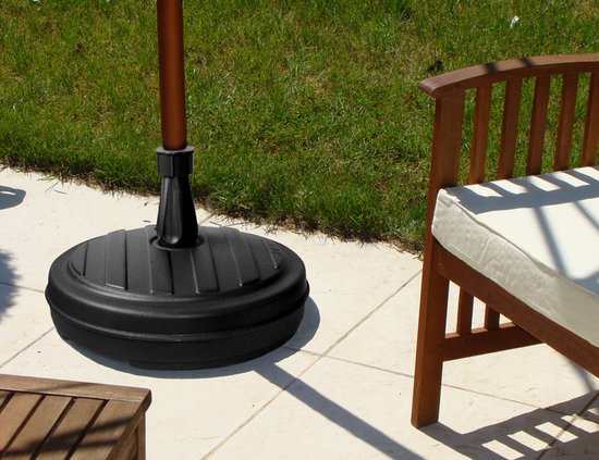 Zwarte parasolvoet in een tuin, naast een houten bank.