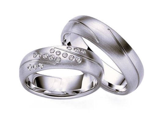 Twee zilverkleurige trouwringen met matte afwerking, gravure en zirkonia steentjes op een ring.