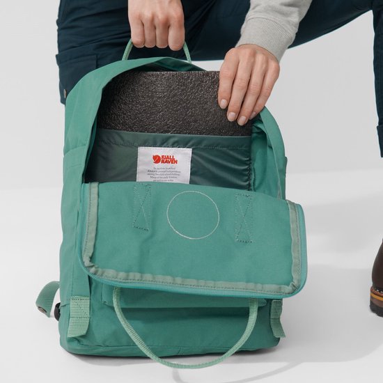 Open groene Fjällräven Kånken rugzak met een laptop erin.