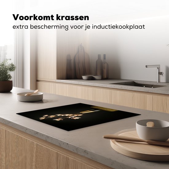 Zwarte inductiebeschermer met boeket bloemen op een aanrecht in een keuken.