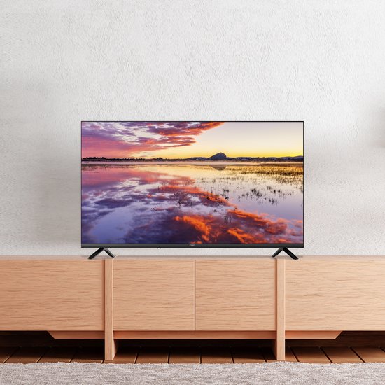CHiQ TV op een houten kastje met een weerspiegeling van een zonsondergang op het scherm.