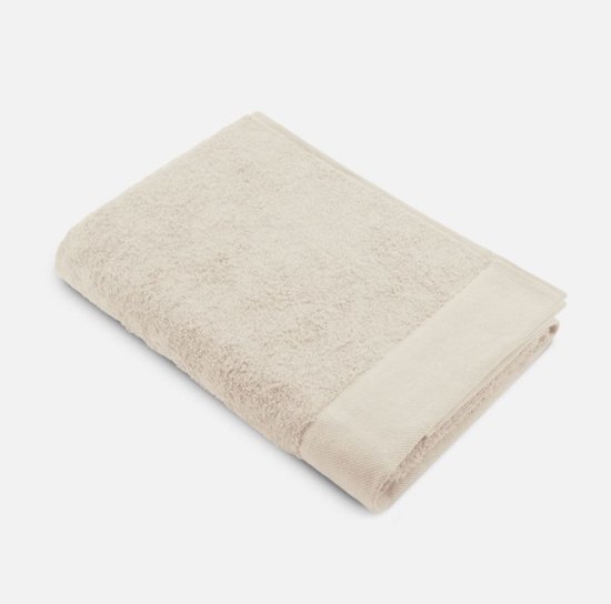 Opgevouwen beige handdoek met een lichte beige band aan de zoom, geïsoleerd op een witte achtergrond.