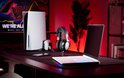Zwarte HyperX gaming headset op standaard, naast een PlayStation 5 en laptop.