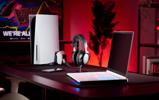 Zwarte HyperX gaming headset op standaard, naast een PlayStation 5 en laptop.