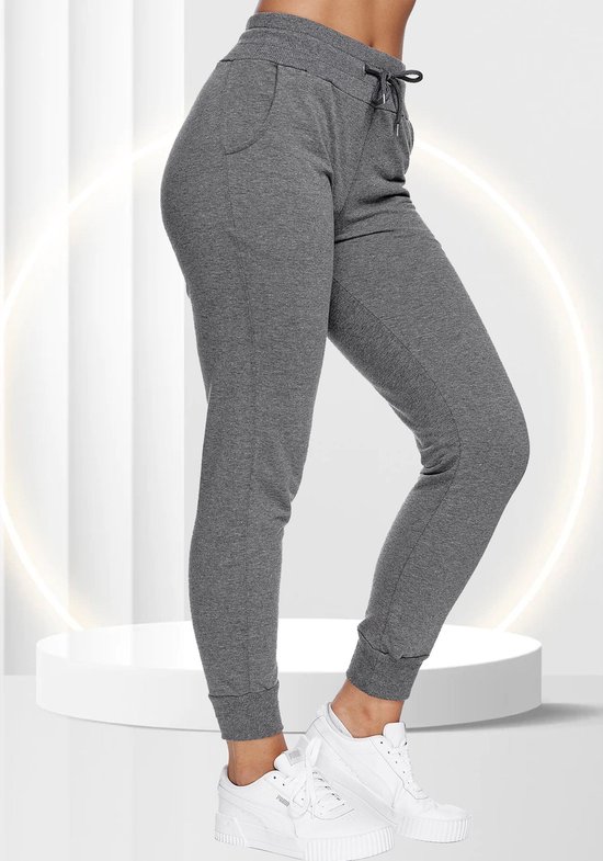 Grijze joggingbroek voor dames, gezien vanaf de zijkant, met witte sneakers en een cirkelvormige lichtdecoratie.