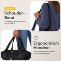 Vrouw draagt zwarte reistas met schouderband en handvat, tekst 'Praktische Schouderband'.