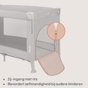 Gedetailleerde weergave van de rits aan de zijkant van het grijze reisbedje. "Zij-ingang met rits" en "Bevordert zelfstandigheid bij oudere kinderen".