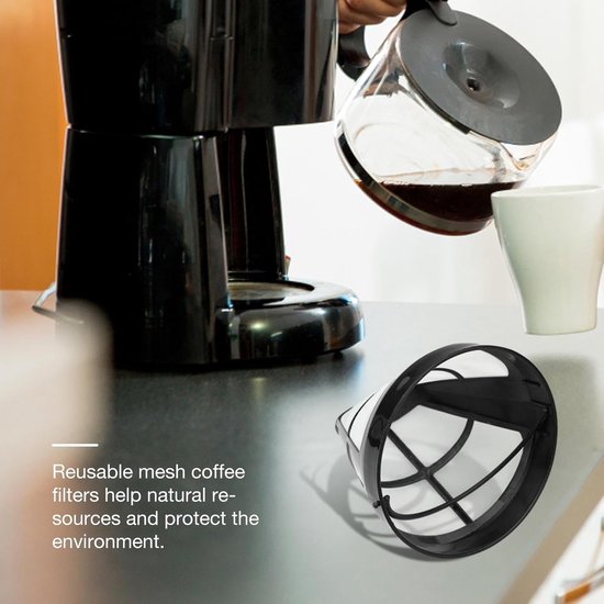 Een zwart herbruikbaar koffiefiltermandje met mesh bodem, naast een koffiezetapparaat.