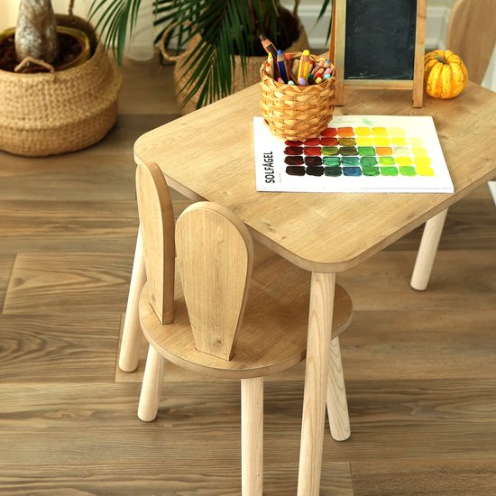 Houten kindertafel met twee stoeltjes met konijnenoren, met een kleurenkaart en potloden.