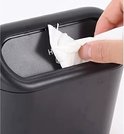 Hand pakt een witte tissue uit een zwart bakje.