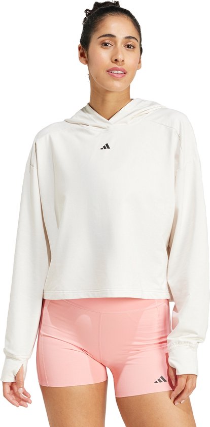 Dames hoodie in het wit met korte pasvorm, capuchon en klein adidas logo, gedragen met roze shorts.