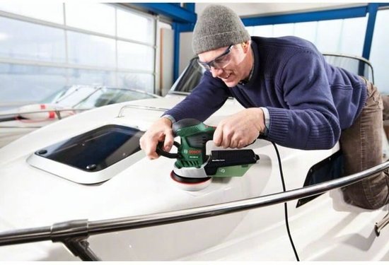 Man met grijze muts schuurt de boeg van een witte boot.