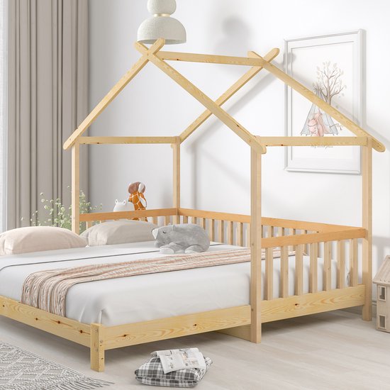 Houten huisbed met spijlen en matras, versierd met knuffels en een deken. Een bijpassende nachtkastje staat ernaast.
