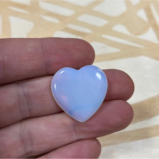 Wit opalieten hart in een hand, met iriserende reflecties.