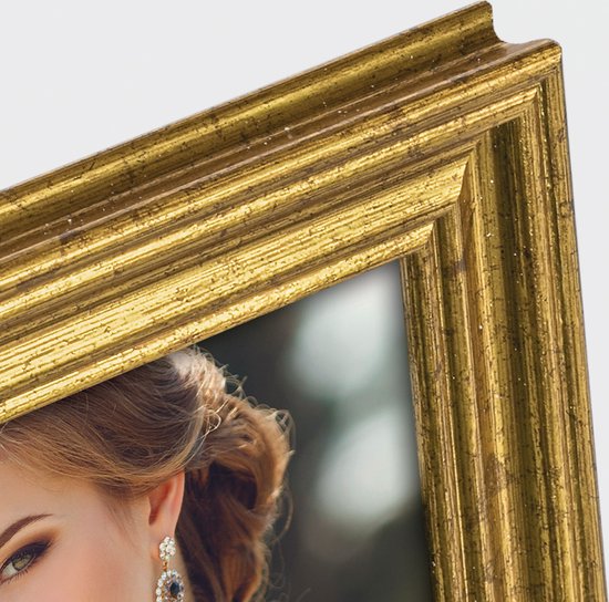 Close-up van een vrouw met opgestoken haar, oogmake-up en oorbellen, naast een gouden fotolijst.