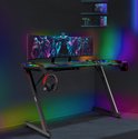 Gaming bureau met RGB verlichting, aan de muur gemonteerde schappen, computer en headset.