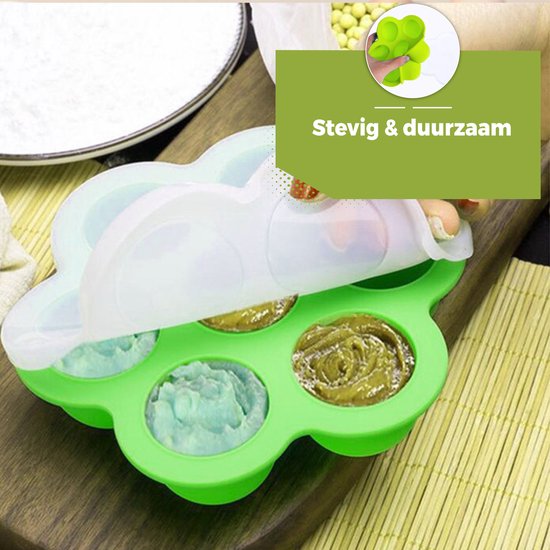 Groen siliconen bakje in bloemvorm, deels bedekt met een wit deksel. Gevuld met babyvoeding in pastelkleuren.