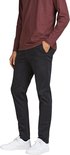 Man in zwarte slim fit chino broek en bordeaux rode longsleeve, met de hand in de zak.