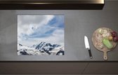 Inductieplaat Beschermer - Besneeuwde Bergtoppen van Alpen Gebergte met Openbrekend Wolkenveld - 60x52 cm - 2 mm Dik - Inductie Beschermer - Bescherming Inductiekookplaat - Kookplaat Beschermer van Wit Vinyl