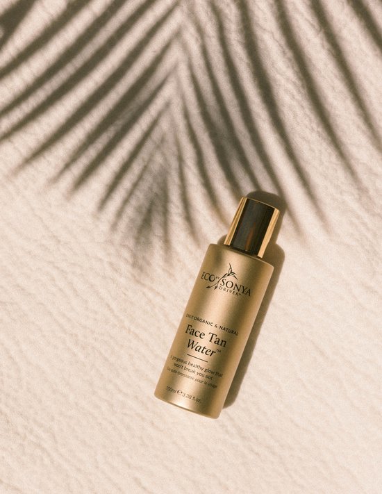 Gouden fles Face Tan Water van Eco Sonya Driver, met palmblad schaduw.