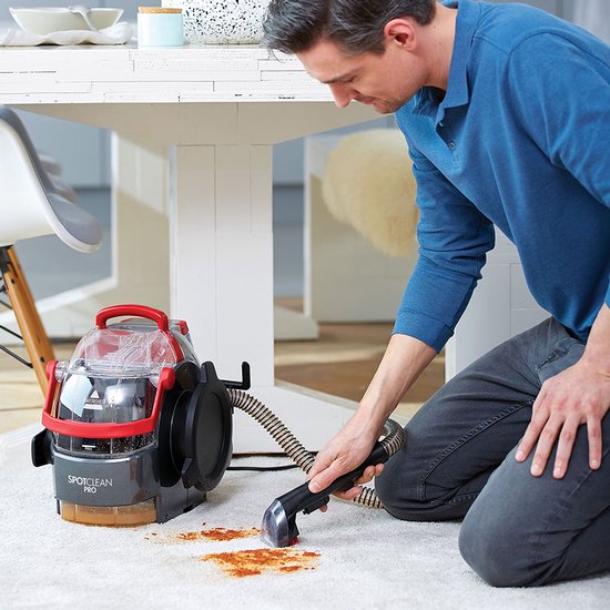 Man reinigt een wit tapijt met de BISSELL SpotClean Pro.