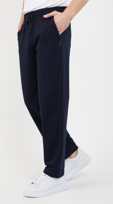 Donkerblauwe joggingbroek met trekkoord, gedragen door een man met een wit T-shirt en witte sneakers, vanuit de zijkant gezien.