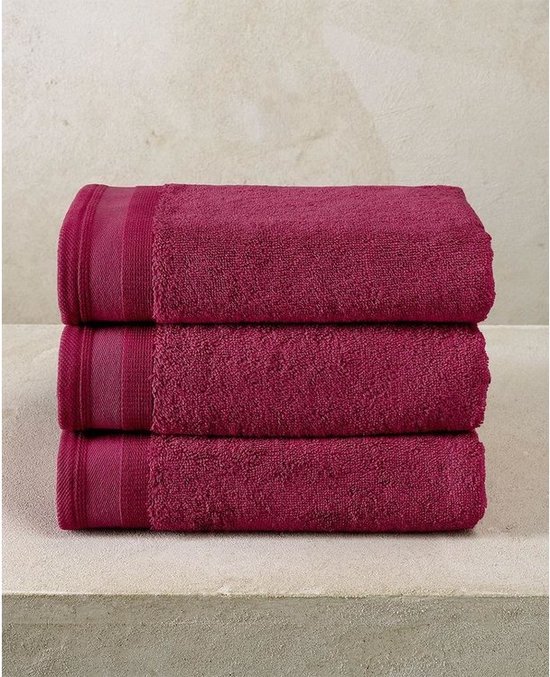 Trois serviettes aubergine empilées avec une double rayure sur le bord supérieur.
