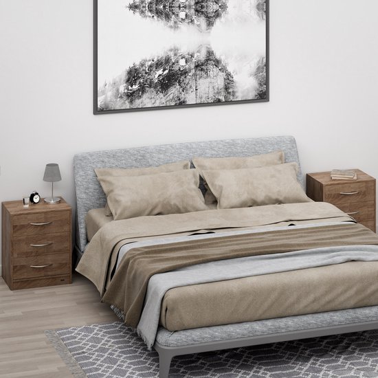 Een slaapkamer met een tweepersoonsbed met bruin en beige beddengoed. Twee lichtbruine, houtnerf nachtkastjes met drie laden staan aan weerszijden van het bed.