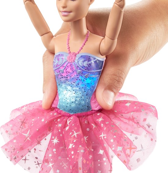 Close-up van Barbie ballerina's korset met blauwe, paarse en roze gloed, roze tutu met zilveren sterren, in een hand.