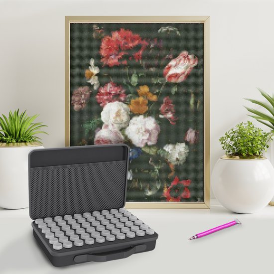 Boîte de rangement noire pour diamants, à côté d'un tableau de fleurs encadré et de plantes.