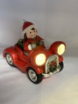 Kerstbeeldje meisje in rode auto met LED - koplampen + groen cadeau - polyresin - 12 cm hoog x 16 cm x 8 cm – Kerstdecoratie