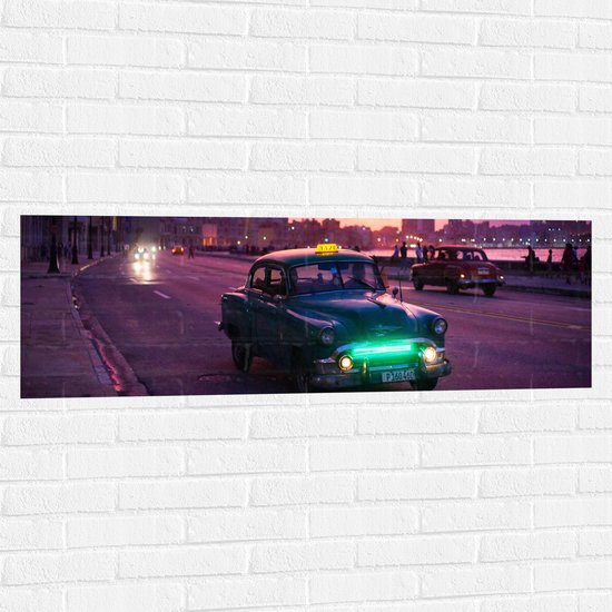 WallClassics - Muursticker - Blauw Taxi in Paarsgekleurde Stad - 120x40 cm Foto op Muursticker