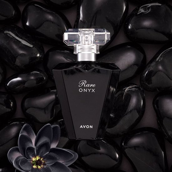 Zwarte, facet geslepen parfumfles 'Rare ONYX' van Avon, omringd door zwarte stenen en een zwarte bloem.