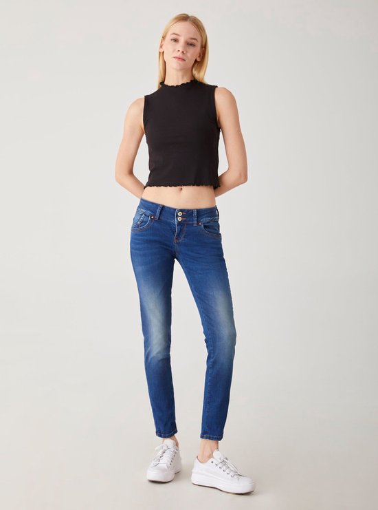 Model in een zwarte crop top met ruches en een donkerblauwe skinny jeans met medium wassing.