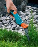Hand gebruikt blauwe Gardena graschaar om gras te knippen.