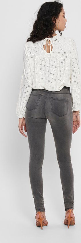 Vrouw van achteren gezien in grijze skinny jeans en een witte top.