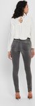 Vrouw van achteren gezien in grijze skinny jeans en een witte top.