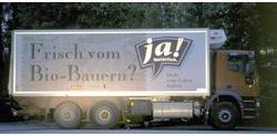Bruine vrachtwagen met witte laadbak met logo 'ja!' en tekst 'Frisch vom Bio-Bauern?'.