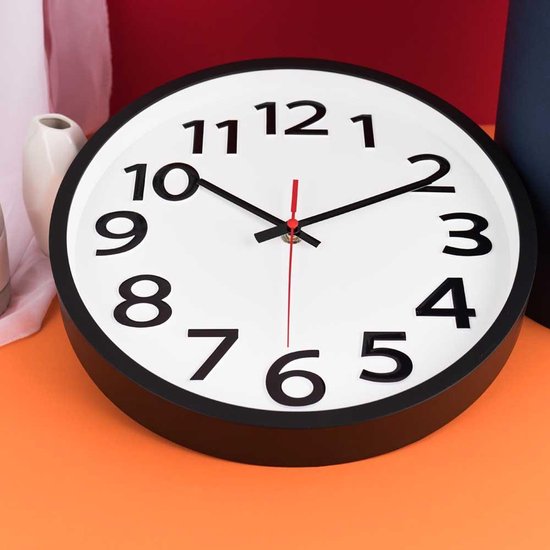 Witte wandklok met zwarte cijfers, op een oranje ondergrond, de klok wijst twee uur aan.