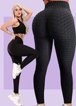Model in zwarte sportset met wafeltextuur, inclusief legging met hoge taille die het figuur accentueert.