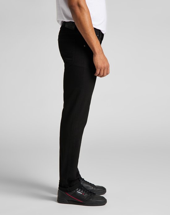 Zijanzicht van een man met zwarte jeans en zwarte sneakers.