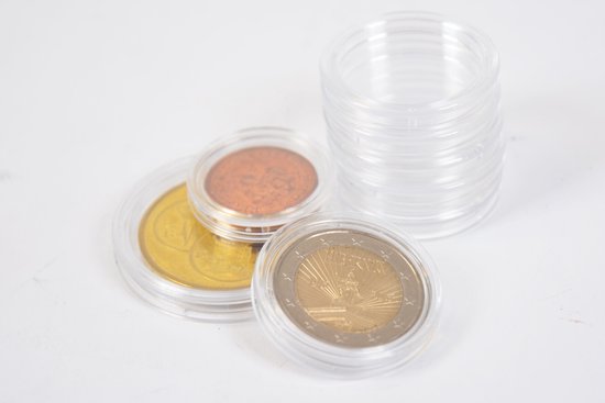 Drie munten in beschermende plastic capsules, met een stapel lege capsules op de achtergrond.