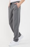 Pantalon de jogging gris foncé pour hommes avec cordon noir et poche latérale, porté avec des baskets blanches.