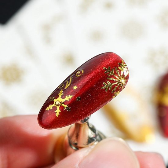 Gouden sneeuwvlokjes en sterren op een glanzende rode nagel.