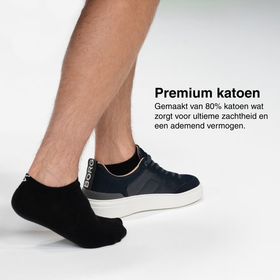 Man met zwarte sokken en blauw met witte sneakers. Zwarte sokken met logo op de enkel.