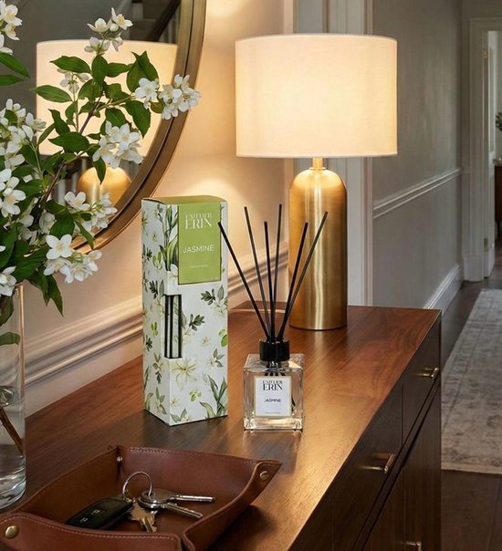 L'Atelier Erin Jasmijn reed diffuser met zwarte stokjes, naast een doos met jasmijndecoratie, op een houten dressoir.