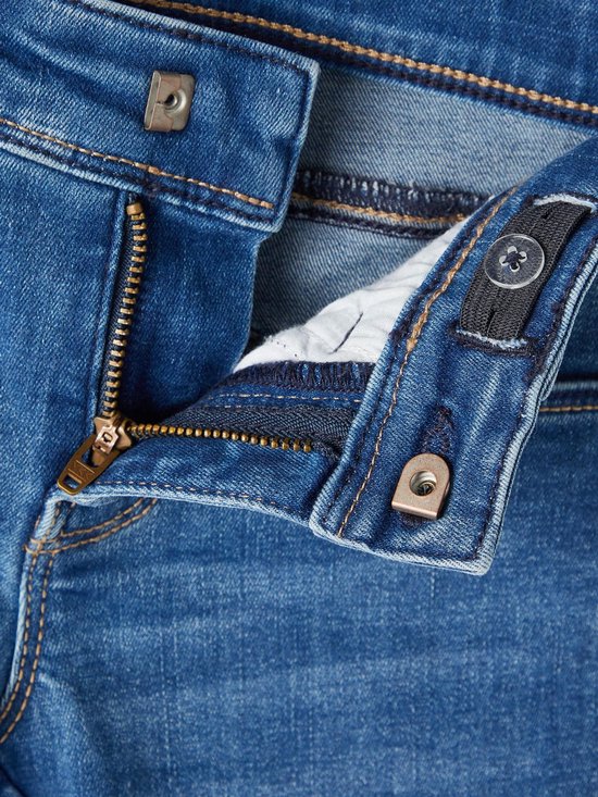 Detail van de tailleband van de jeans met rits en knoop.